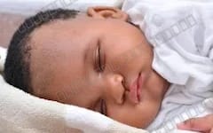 Sleeping newborn baby lying on a white pillow, part of a baby photo product