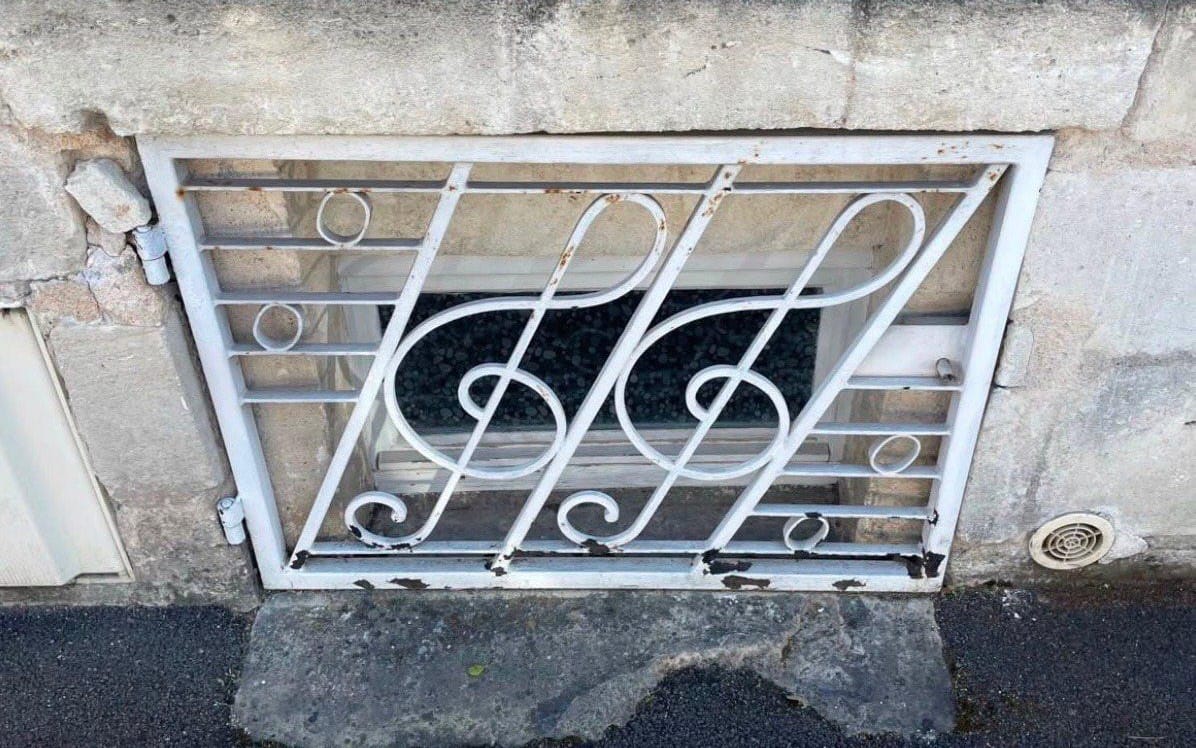 Decorative metal window grille with floral scrollwork on a building, digital art asset titled stash + 5 mels