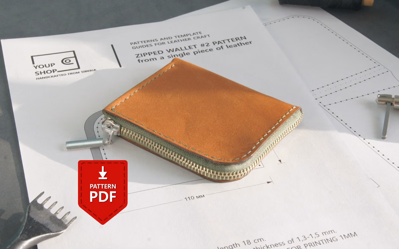 Printed PDF pattern for a zippered leather wallet #2 with template lines, tools, and a finished wallet on top