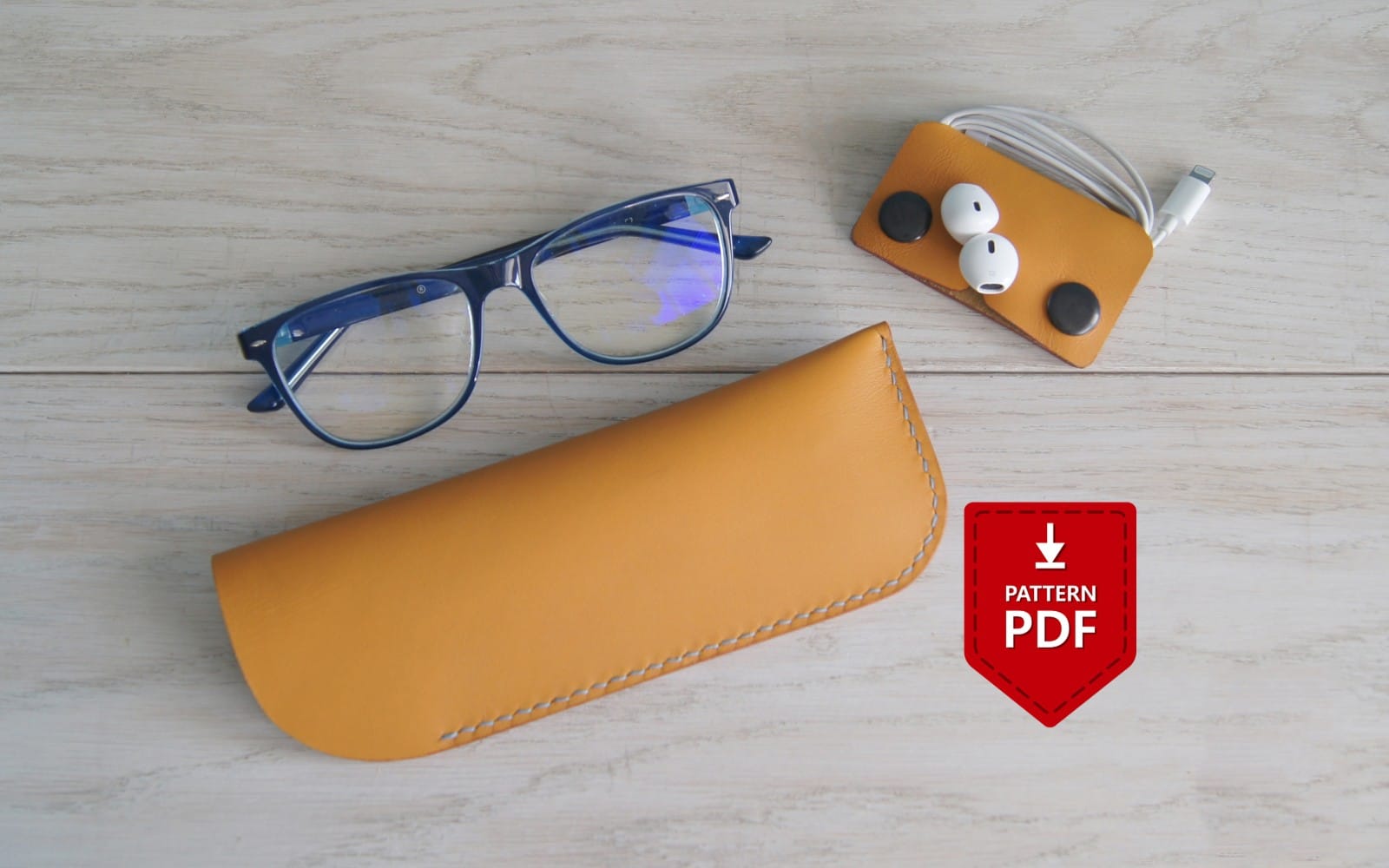 Leather eyeglasses case pattern PDF with glasses, AirPods holder, and charging cables on a wooden surface