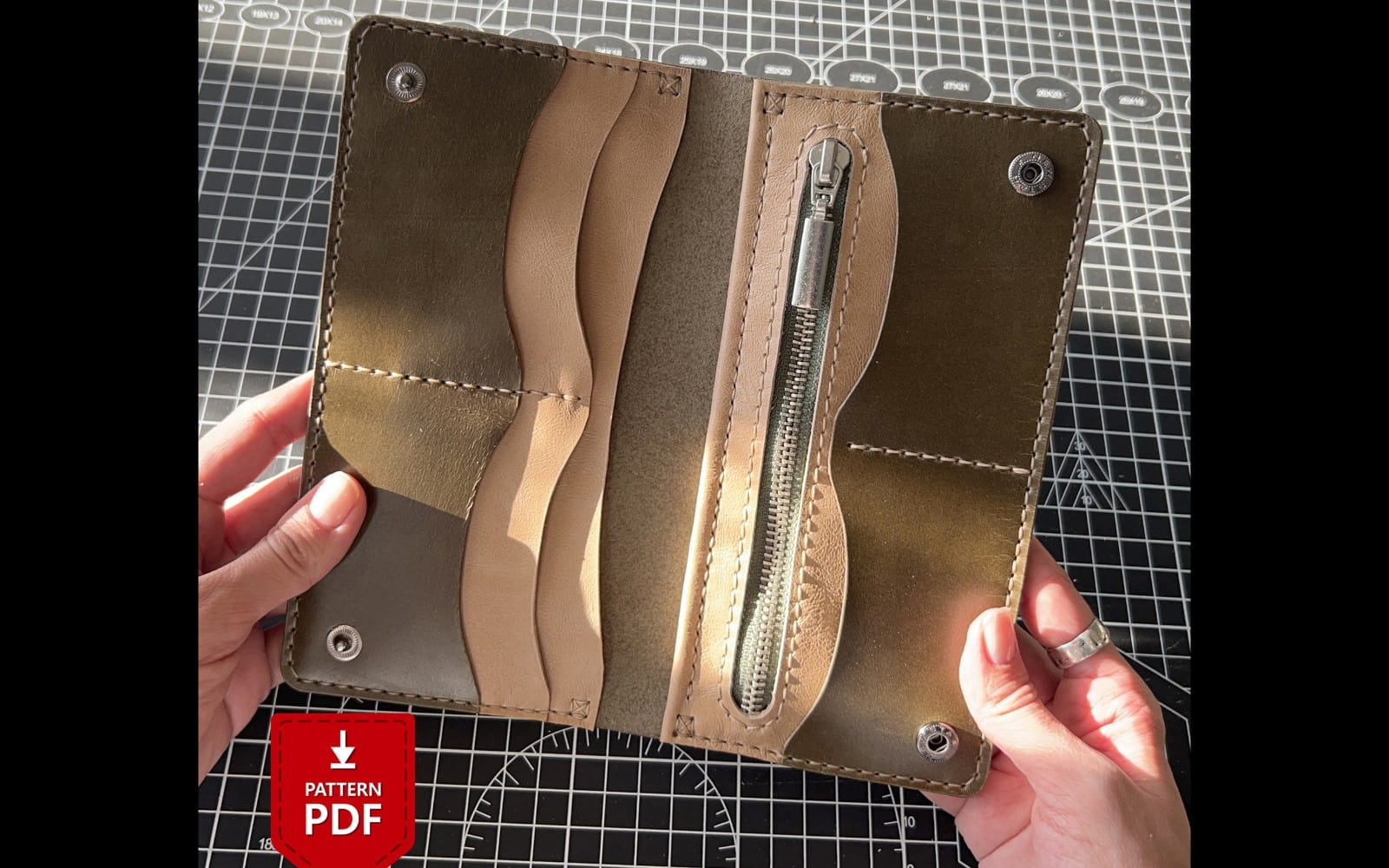 Leather longer wallet interior pattern PDF shown on a cutting mat with hand holding the assembled template