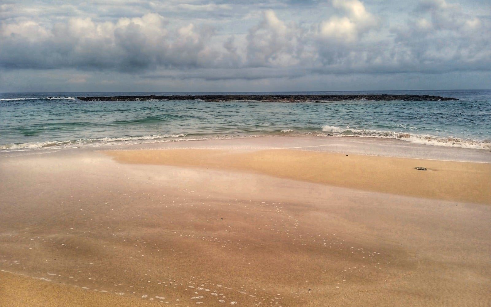 Playa de arena dorada en Varadero con olas rompiendo y cielo nublado, serie de fotografías de vacaciones